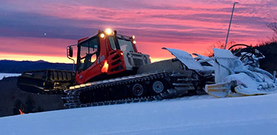 Snow groomer sunset